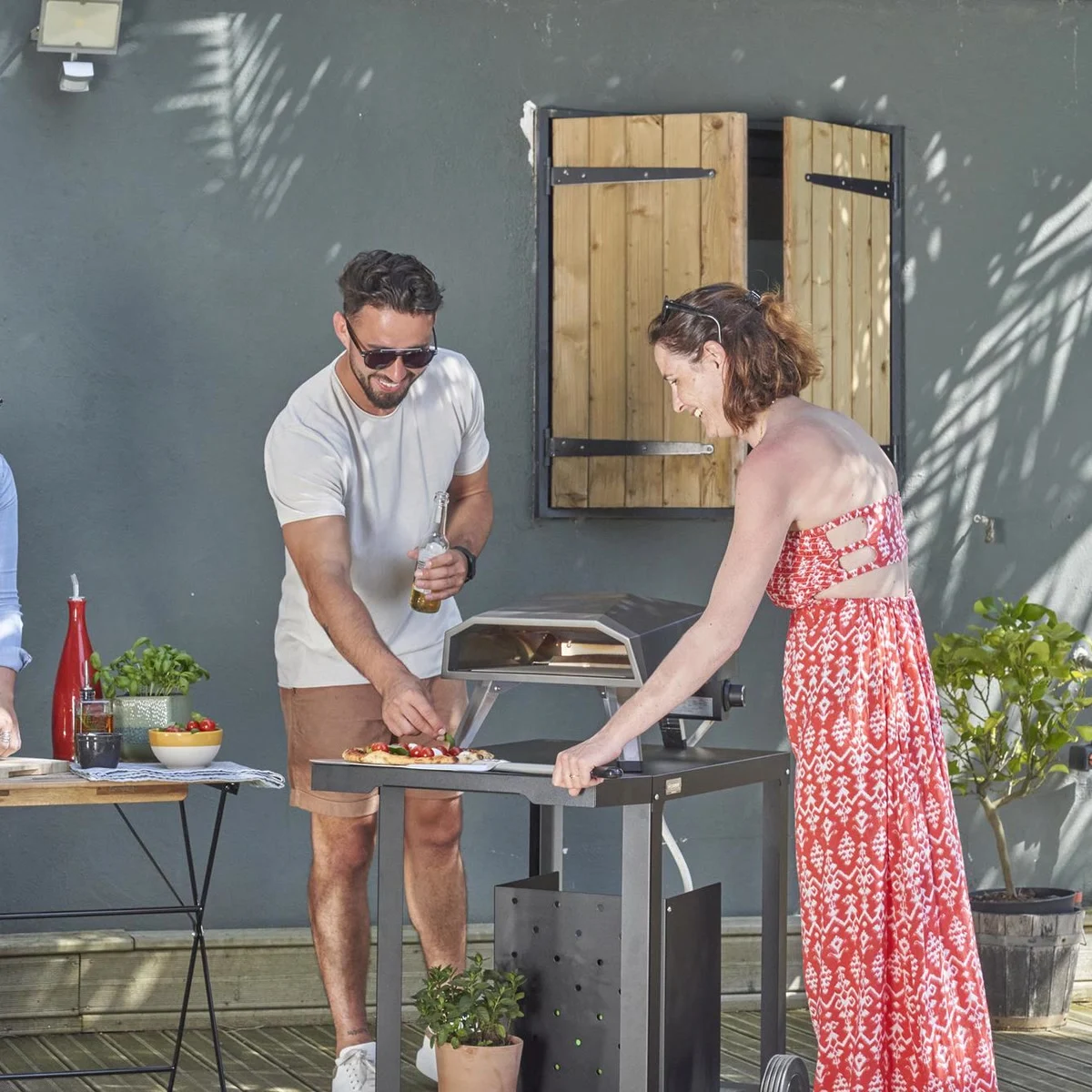 Une pizza garnie sur la pelle devant le four Le Marquier Duo 12", sur une terrasse