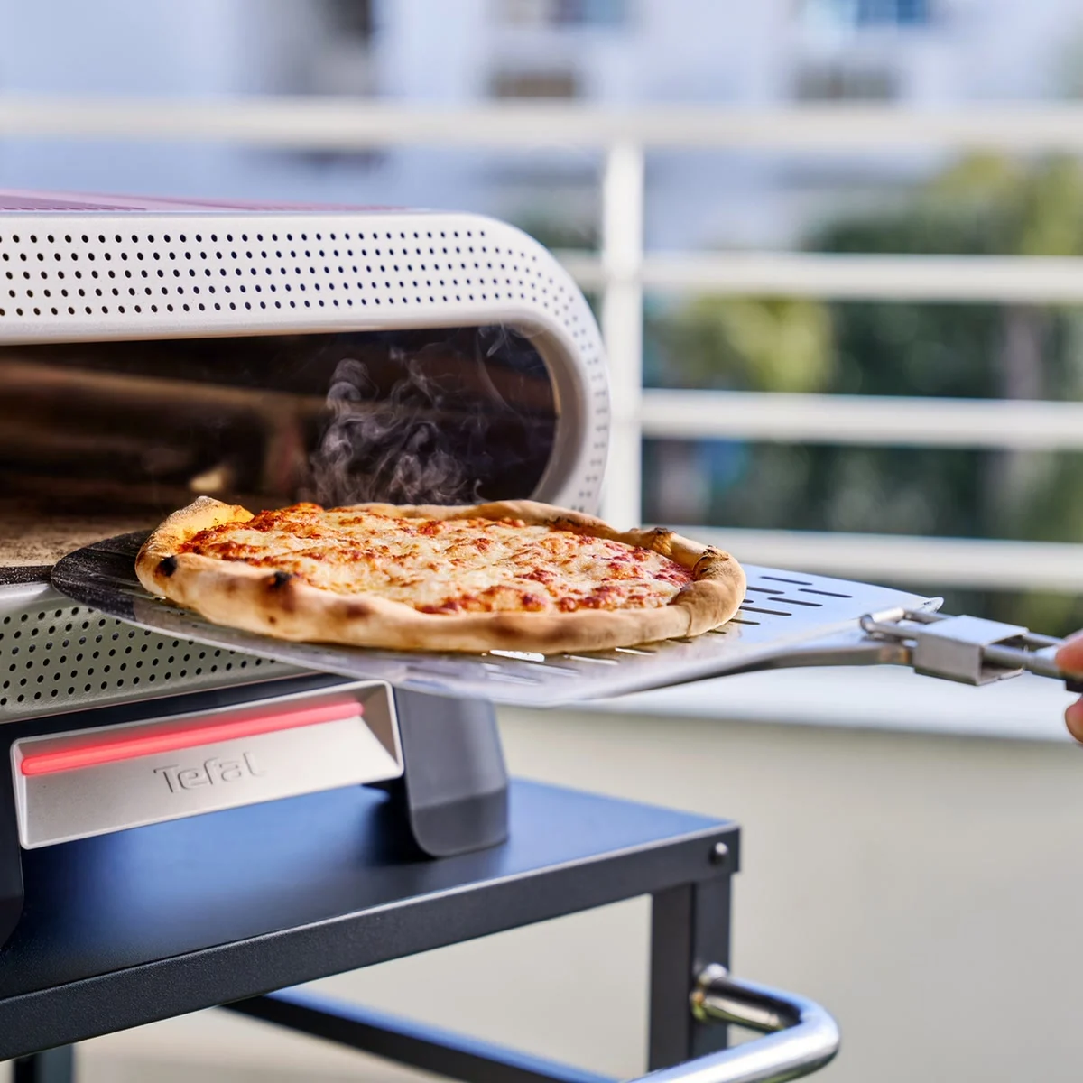 Tefal Pizza Pronto sur un balcon, une pizza fumante sortie à la pelle