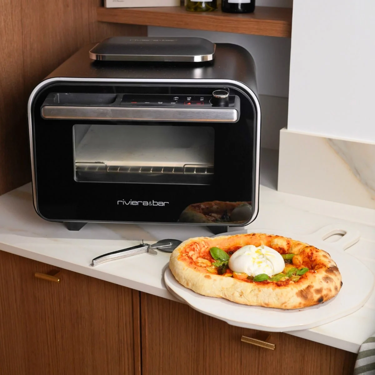 riviera&bar QFP550 sur le plan de travail d’une cuisine, une pizza à la burrata posée devant