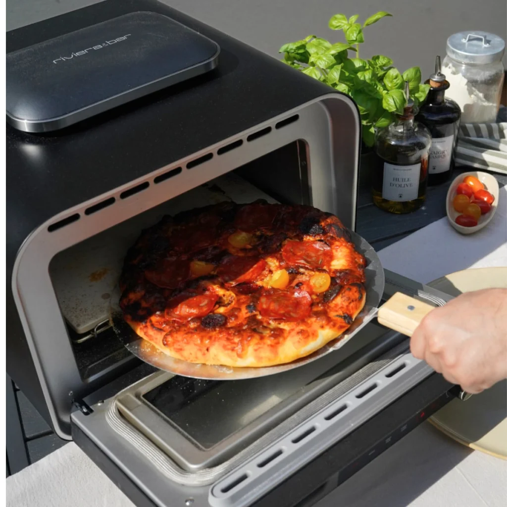 Une pizza cuite sortie du riviera&bar QFP550 avec la pelle, en extérieur