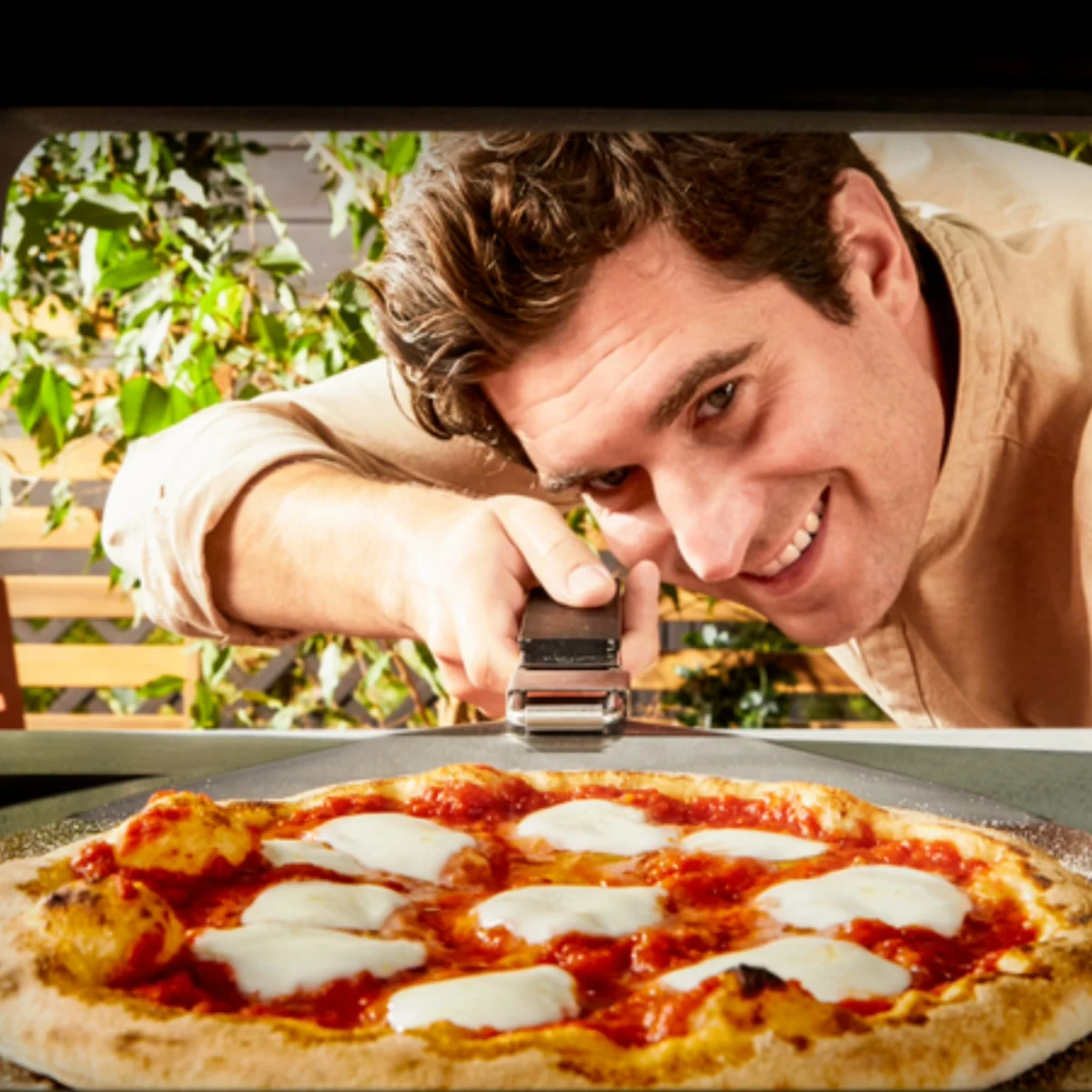Vue depuis l’intérieur du Tefal Pizza Pronto Gaz : un homme enfourne une pizza margherita à la pelle