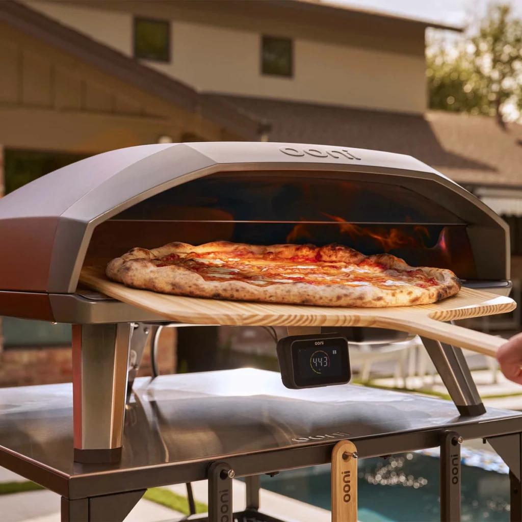 Une grande pizza enfournée à la pelle dans l’Ooni Koda 2 Max, hub de température allumé