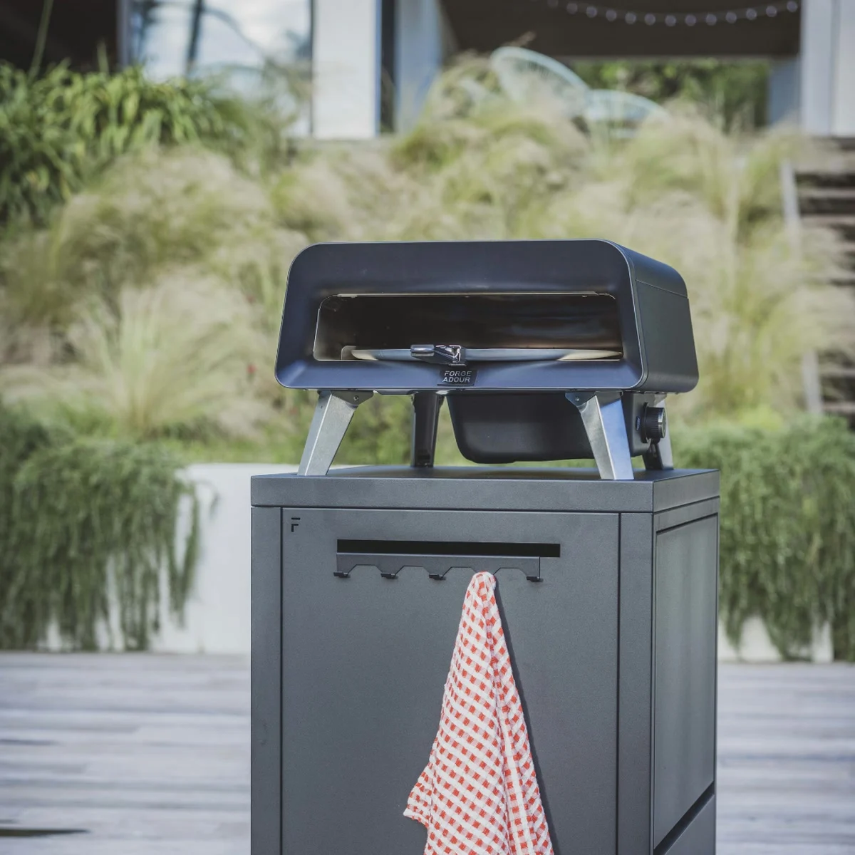 Le four Forge Adour Pro posé sur une desserte grise dans un jardin