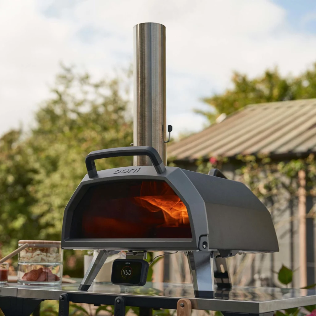 Ooni Karu 2 Pro allumé sur une table inox, flammes derrière la vitre, hub de température en façade