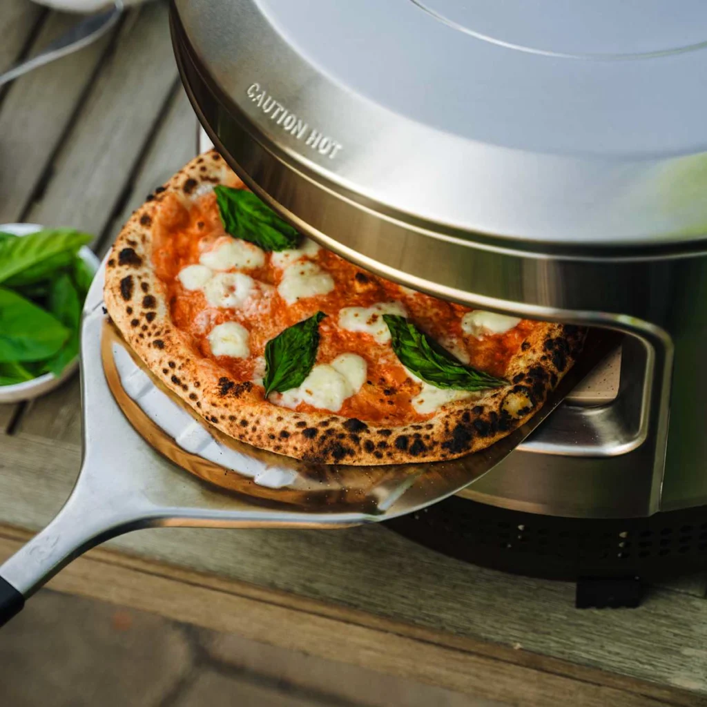 Une pizza margherita sort du Solo Stove Pi Prime sur une pelle en inox