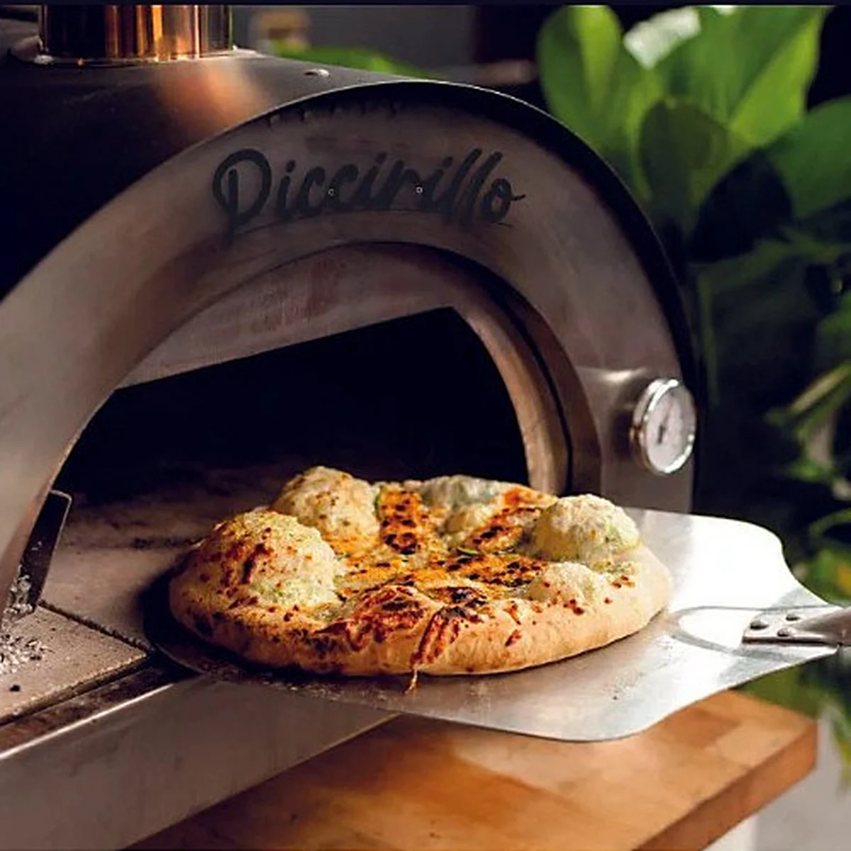 Une pizza dorée sort du Bellanapoli Piccirillo sur une pelle