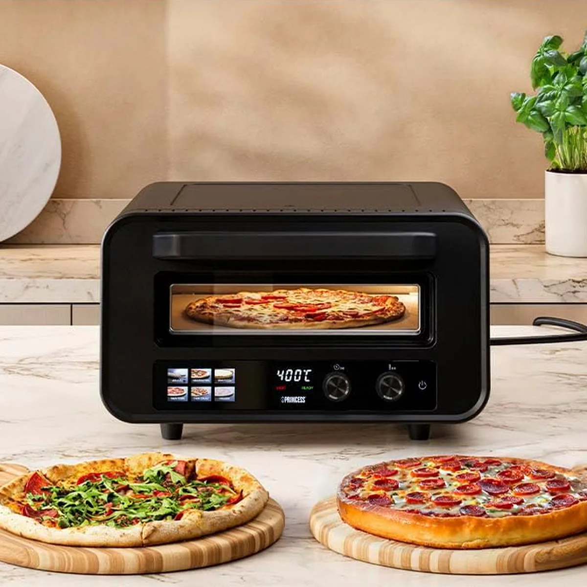 Princess 112780 sur un îlot de cuisine, des pizzas de plusieurs styles posées devant