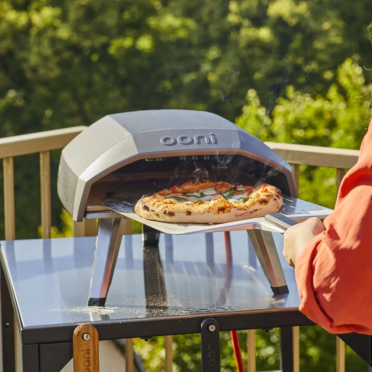 Ooni Koda 12 sur une table en terrasse, une pizza margherita sortie à la pelle